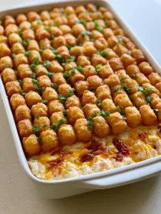 Close up shot of Chicken Bacon Ranch Tater Tot Casserole showing the creamy chicken base and melted cheddar cheese.