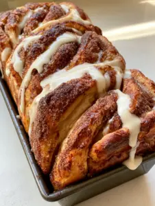 Handheld photo of fresh pull-apart cinnamon bread showing pillowy folds and deep golden-brown crust. (Dollywood Cinnamon Bread)